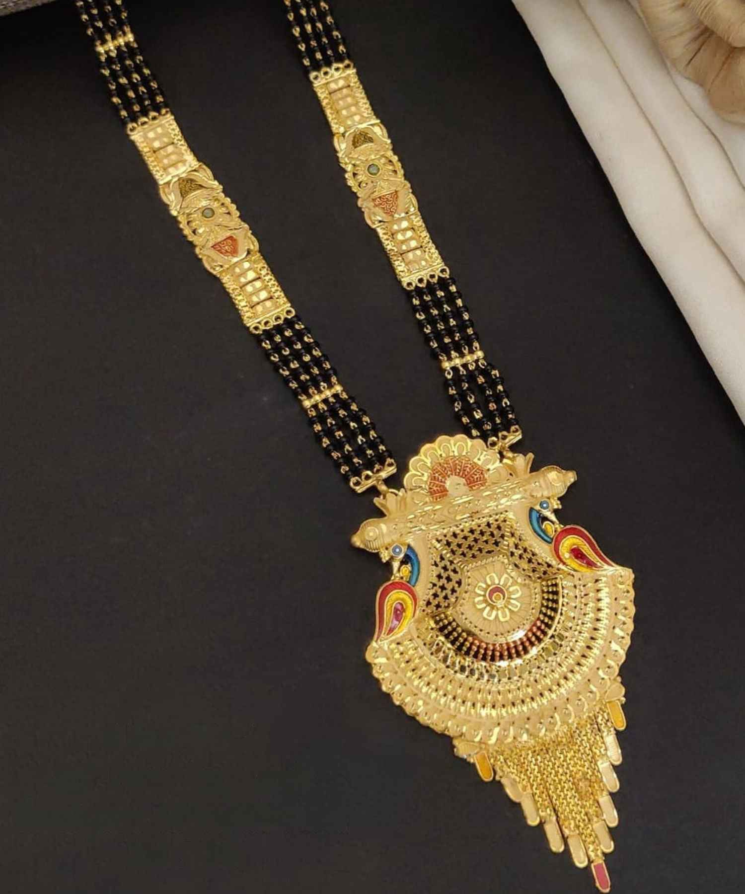 Gold necklace with decorative pendant on a black background