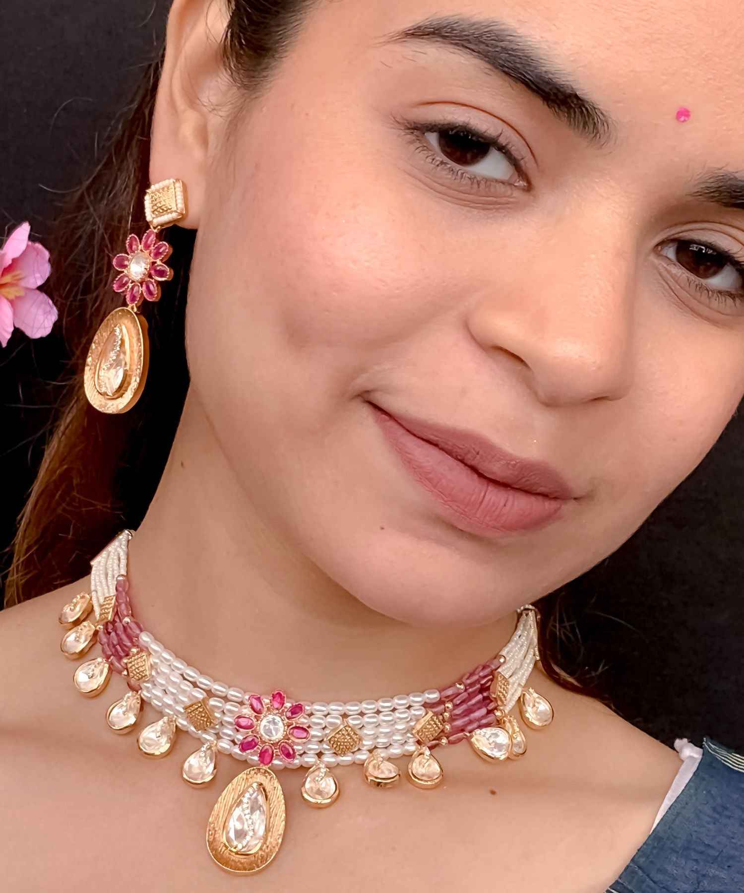 Close-up of a woman wearing a decorative necklace and earrings with a dark background