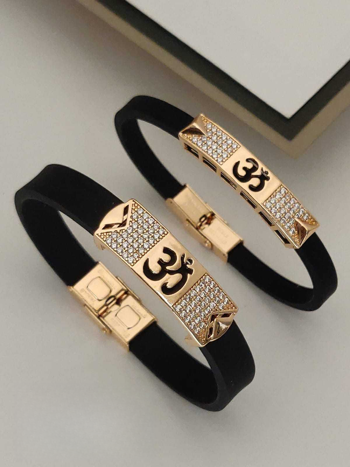 Pair of black bracelets with gold accents and 'Om' symbol on a light gray background