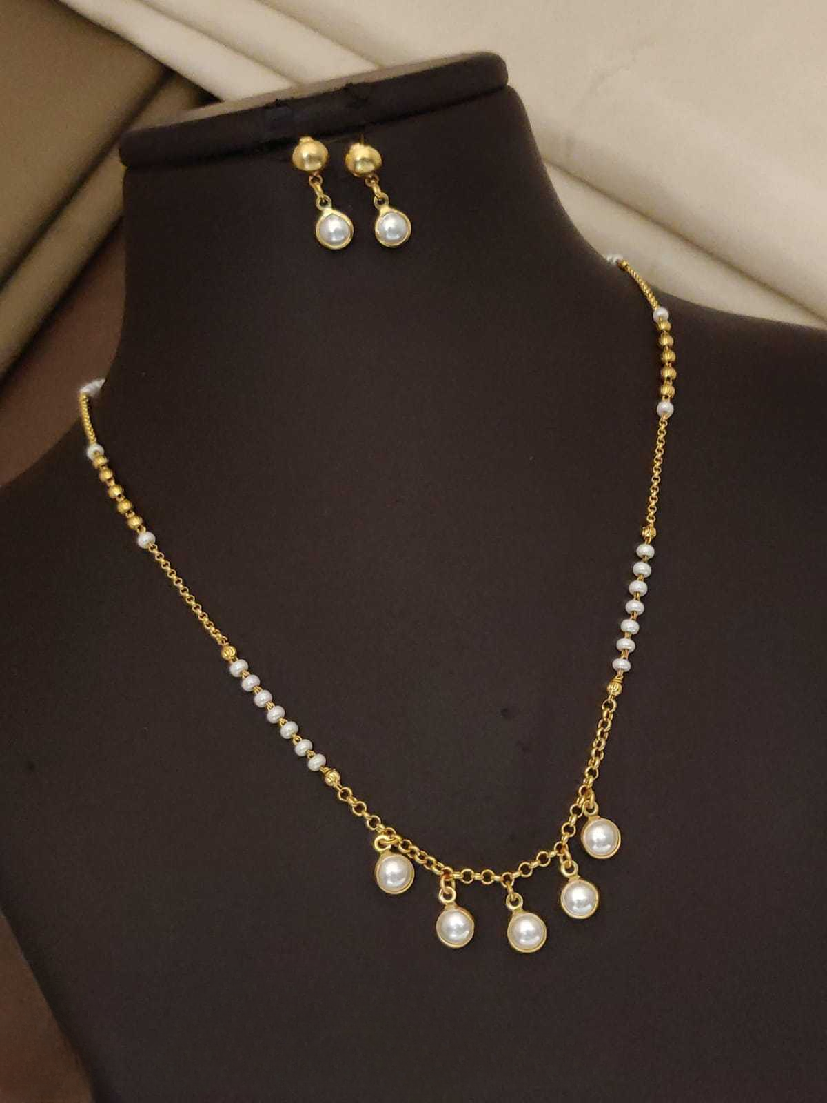 Pearl necklace and earrings on a black mannequin bust.