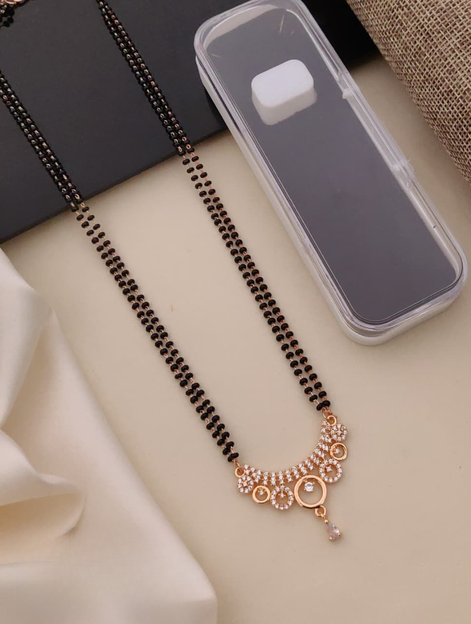 Black beaded necklace with gold and rose gold accents on a beige surface