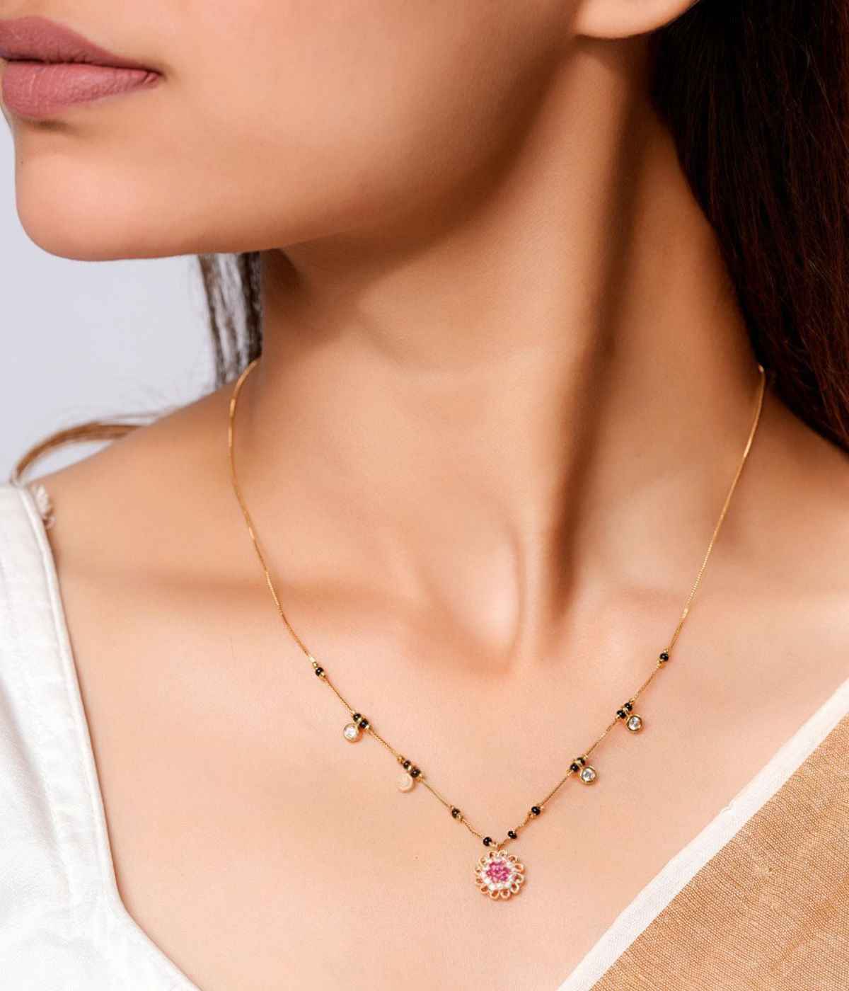 Gold necklace with a pink pendant worn by a model