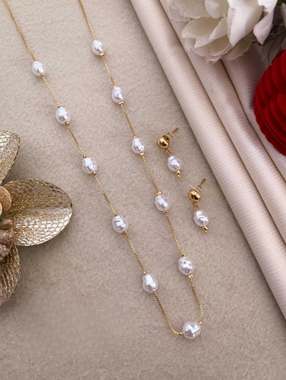 Pearl necklace and earrings on a beige surface with flowers in the background