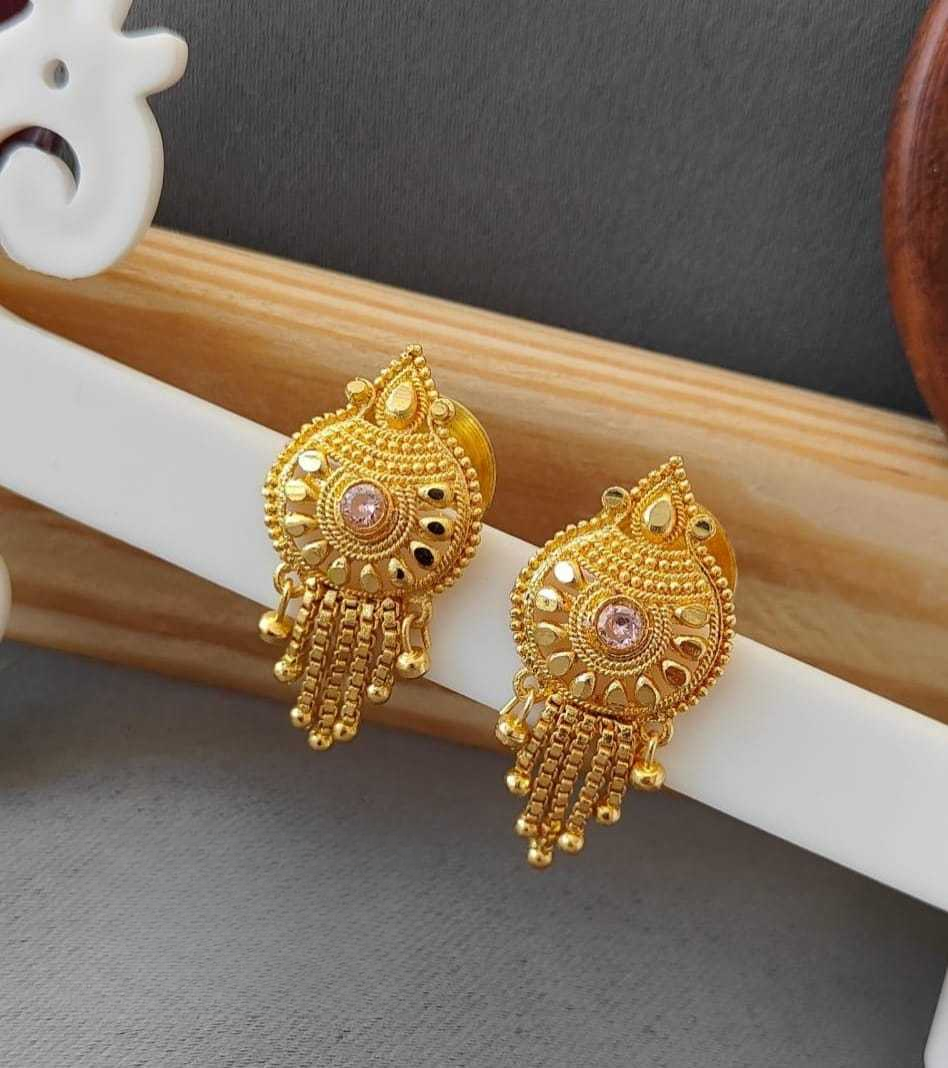 Gold earrings with pink gemstones on a white and brown stick against a gray background