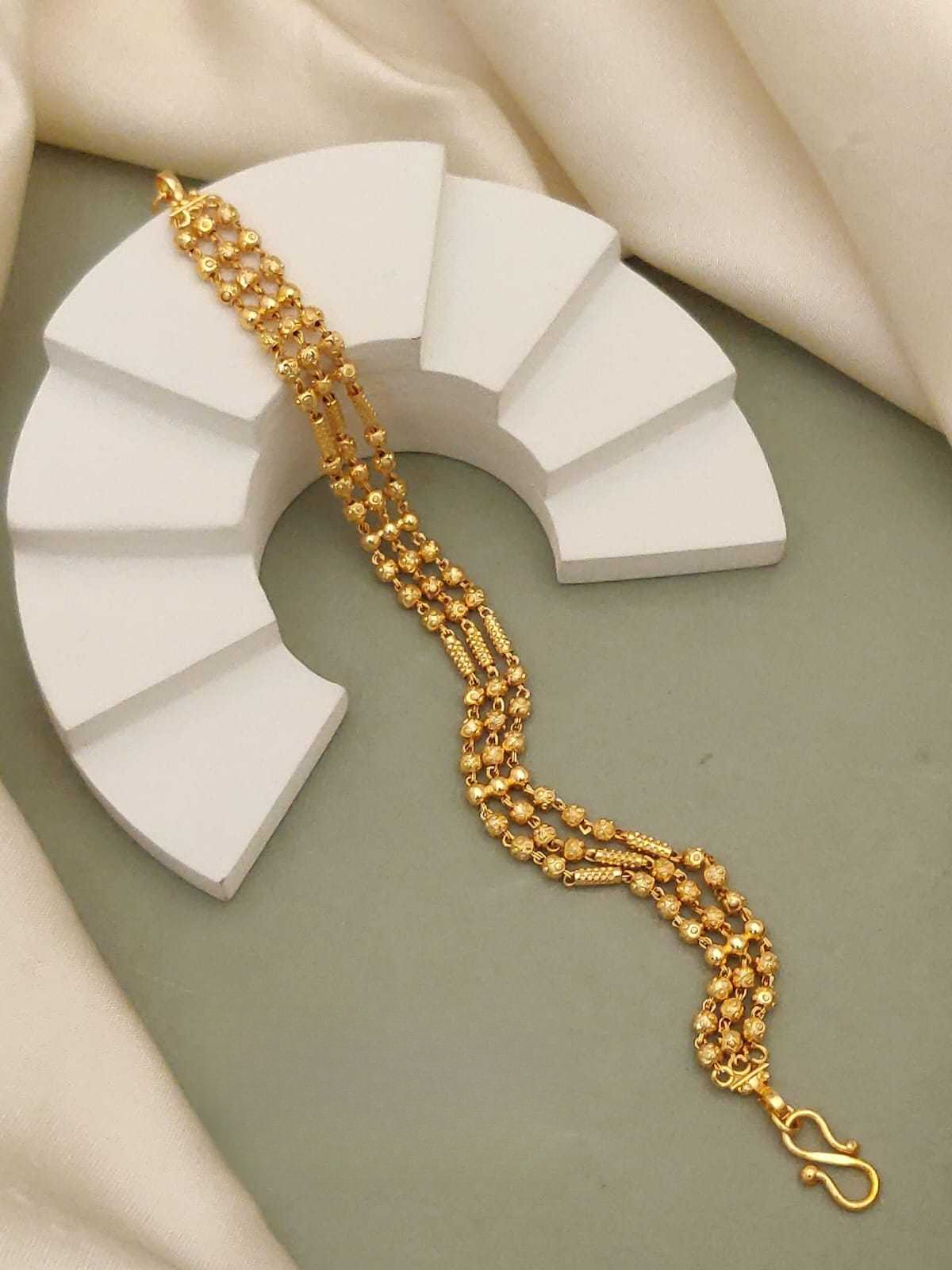 Gold bracelet on a white geometric display piece with a neutral background
