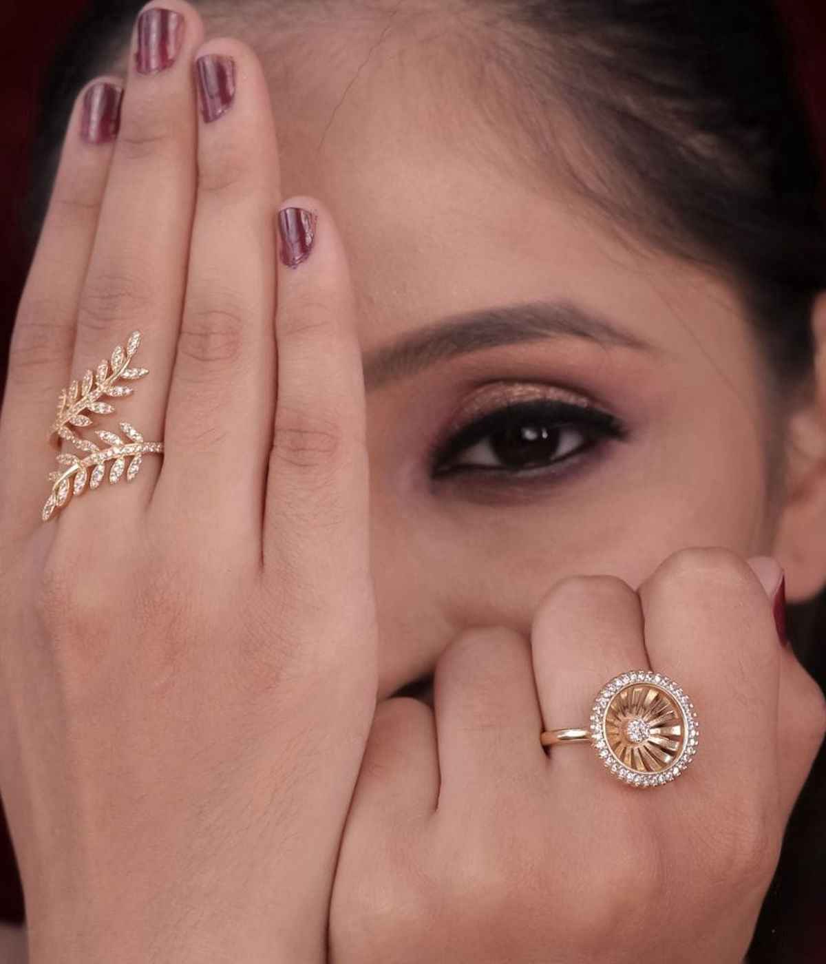 Close-up of a woman's hands wearing two gold rings with intricate designs.