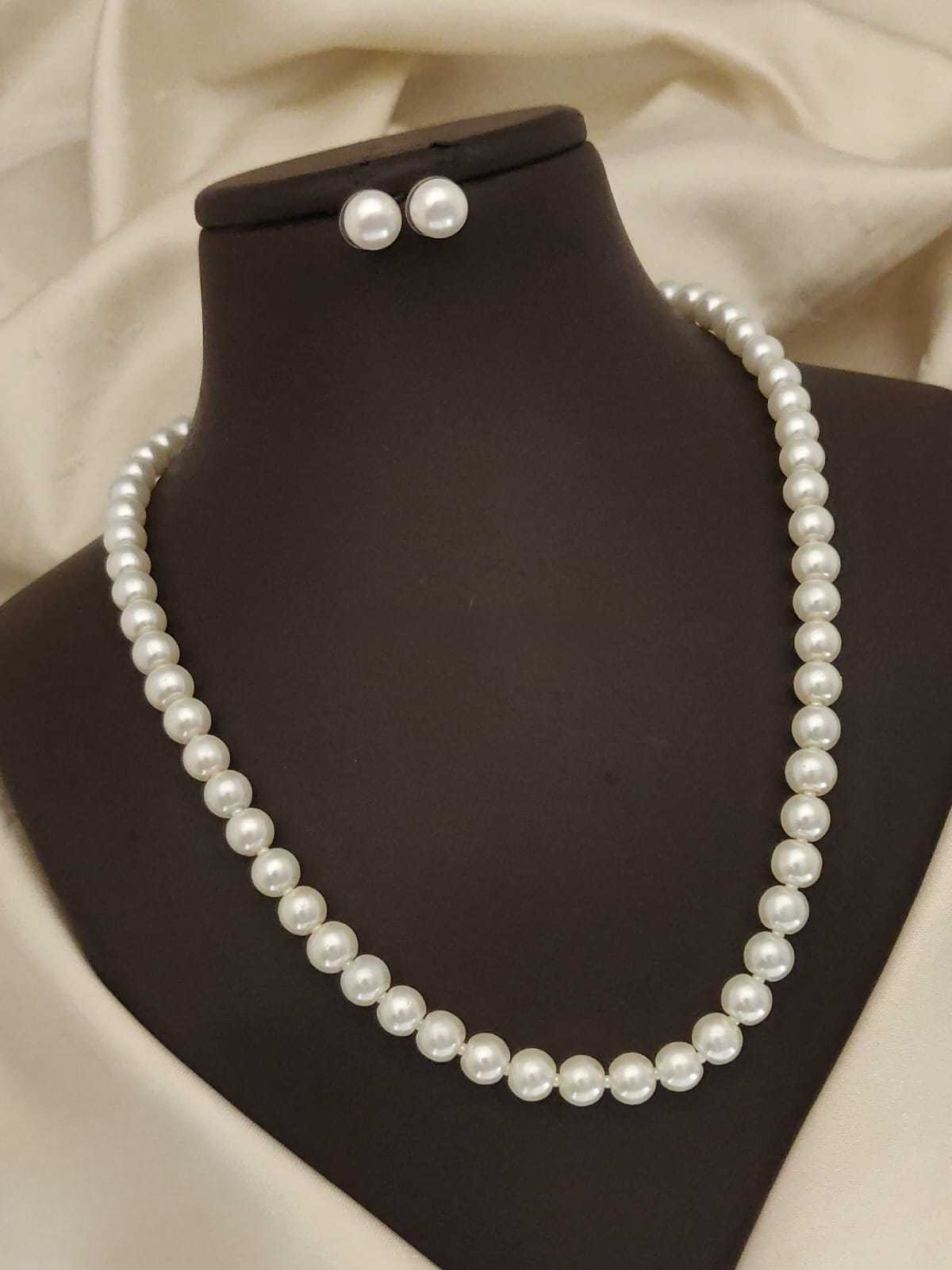 Pearl necklace and earrings on a mannequin bust with a neutral background