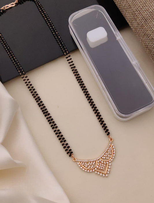 Decorative necklace with black beads and gold accents on a beige surface.