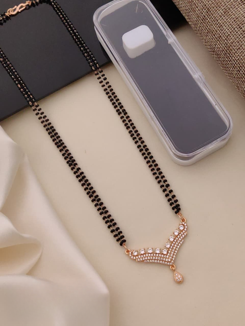 Black beaded necklace with a rose gold clasp on a light surface
