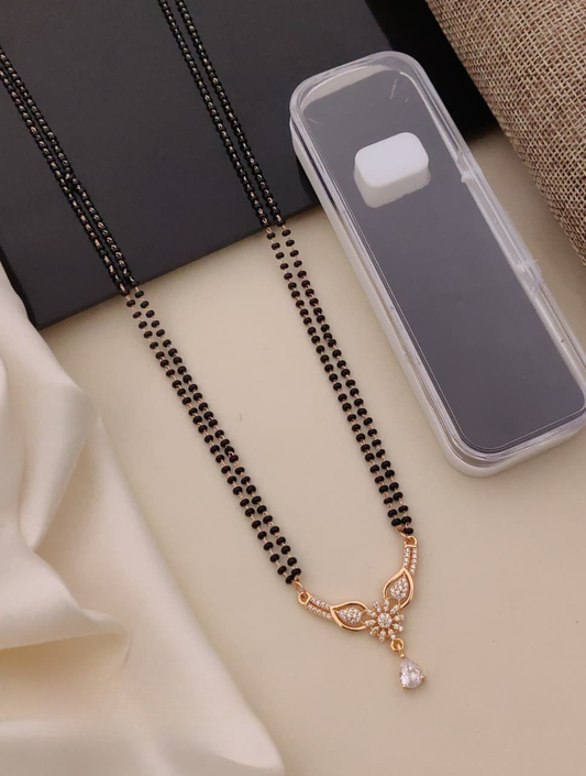 Black beaded necklace with a gold clasp on a beige surface