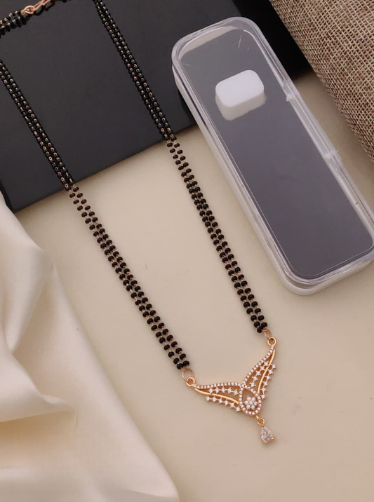 Black beaded necklace with a gold pendant on a light surface