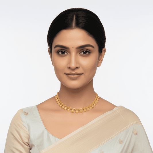 Woman wearing a gold necklace and saree against a light background