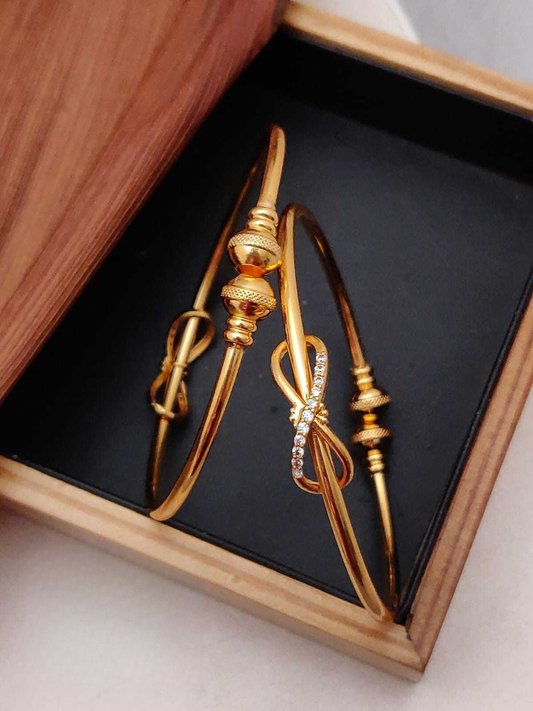 Gold bangles with intricate designs in a wooden box
