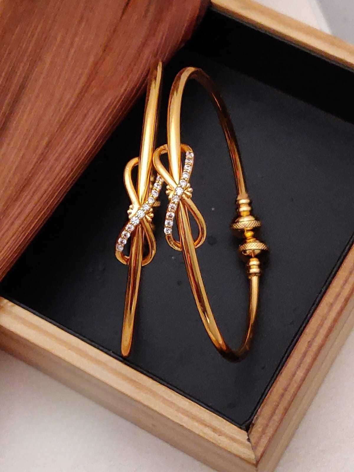 Gold bow-shaped earrings with small diamonds on a black box with wooden sides.