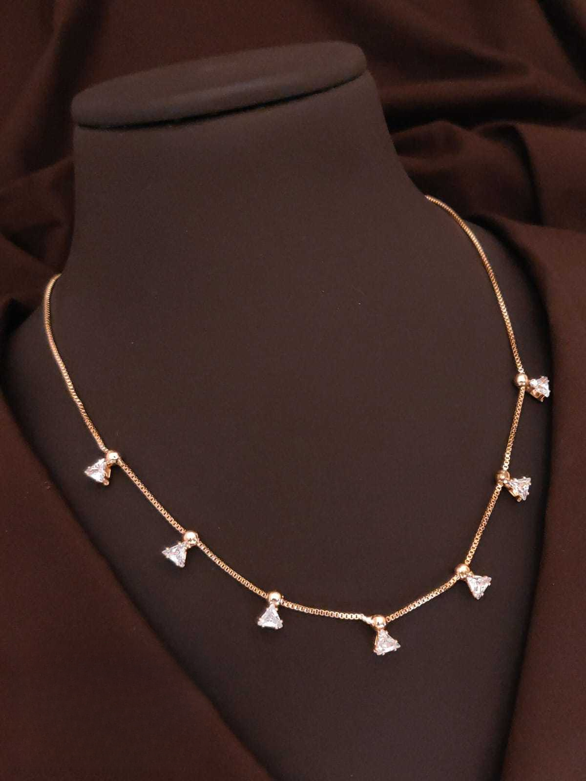 Gold necklace with heart-shaped pendants on a brown fabric background