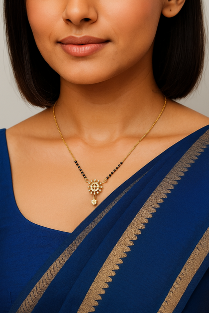 Woman wearing a blue saree with a gold necklace against a neutral background
