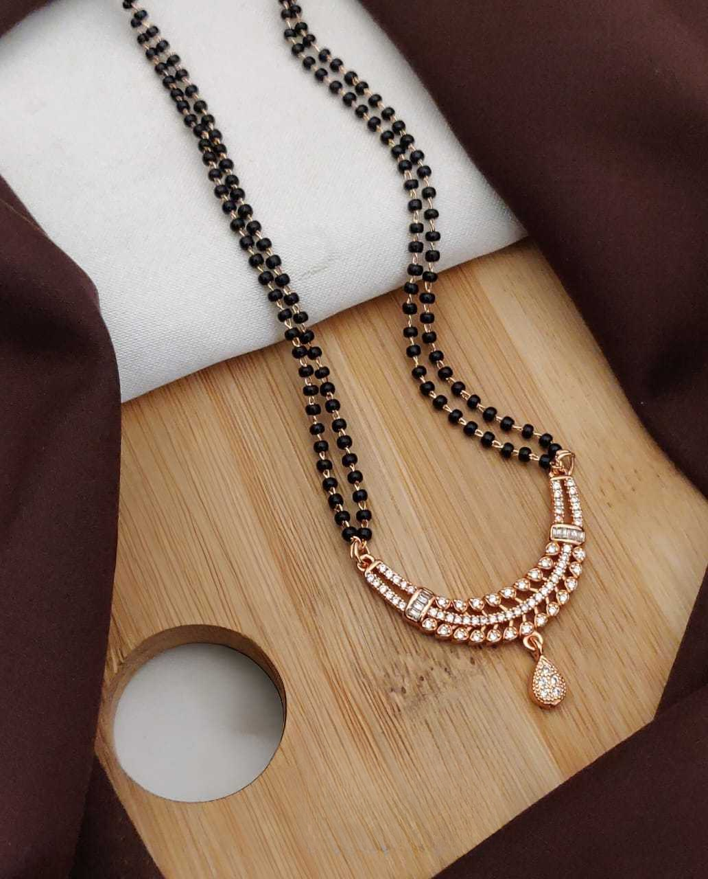 Necklace with black beads and rose gold accents on a wooden surface